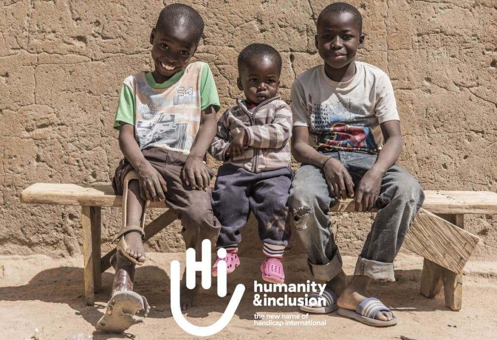 Humanity & Inclusion logo over photo of three boys, one with a leg brace