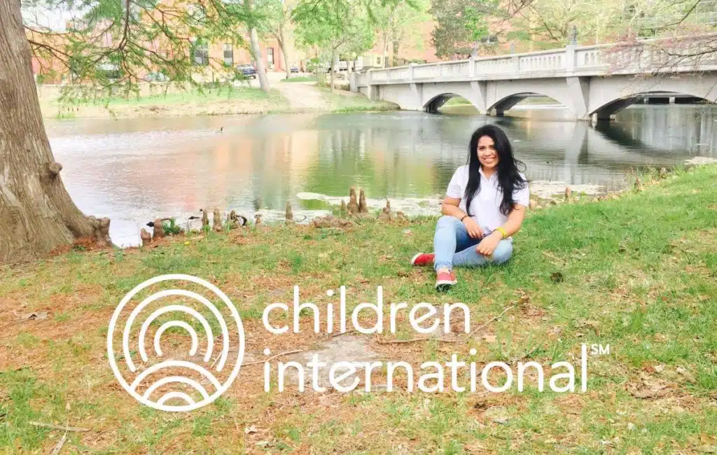 Children International logo over photo of a girl by a river