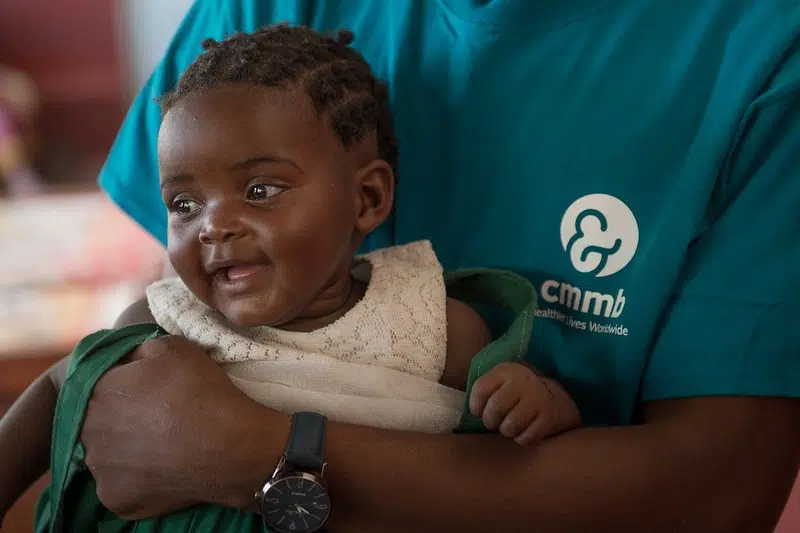 A child being held by a CMMB health care worker.