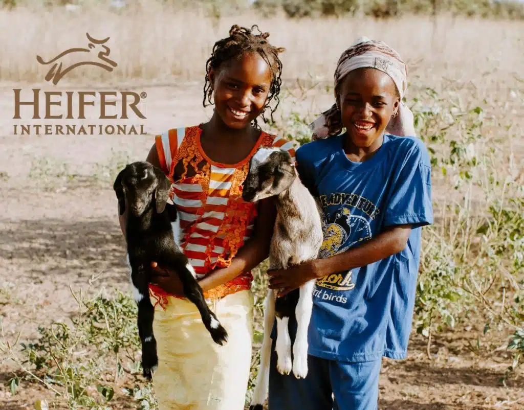 Heifer International logo over a photo of two girls holding goats
