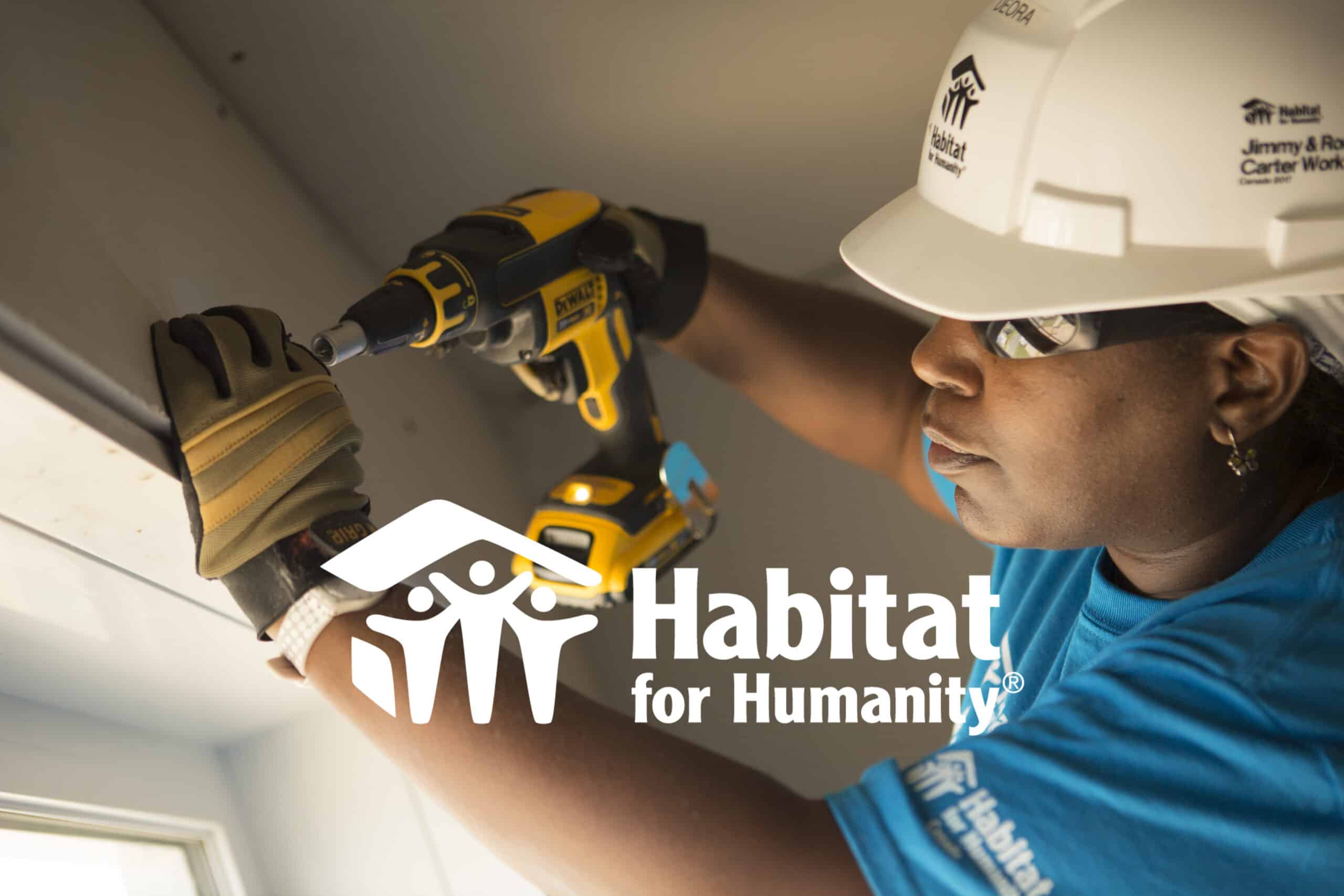 A Habitat for Humanity International worker uses a drill inside of a house.