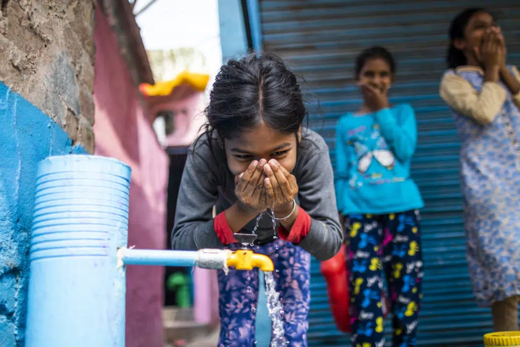 Sneha (10) drinks water from an installed standpost in India