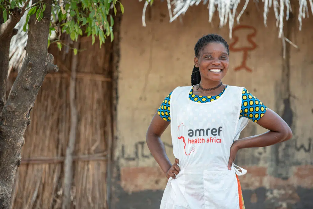 An Amref worked stands smiling with her hands on her hips.