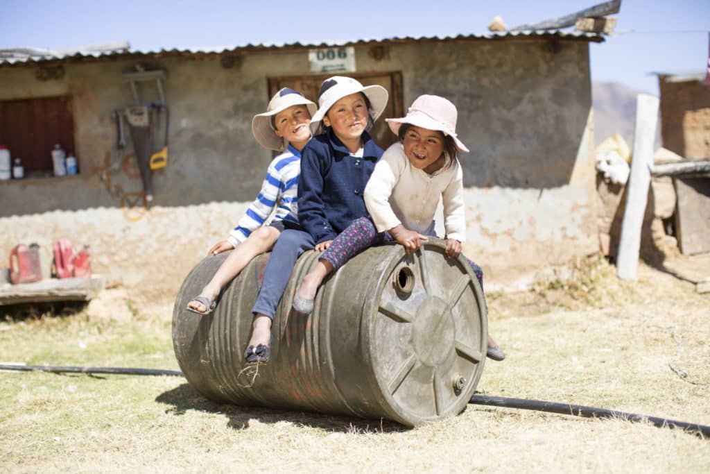 Three children sitting on a barrel