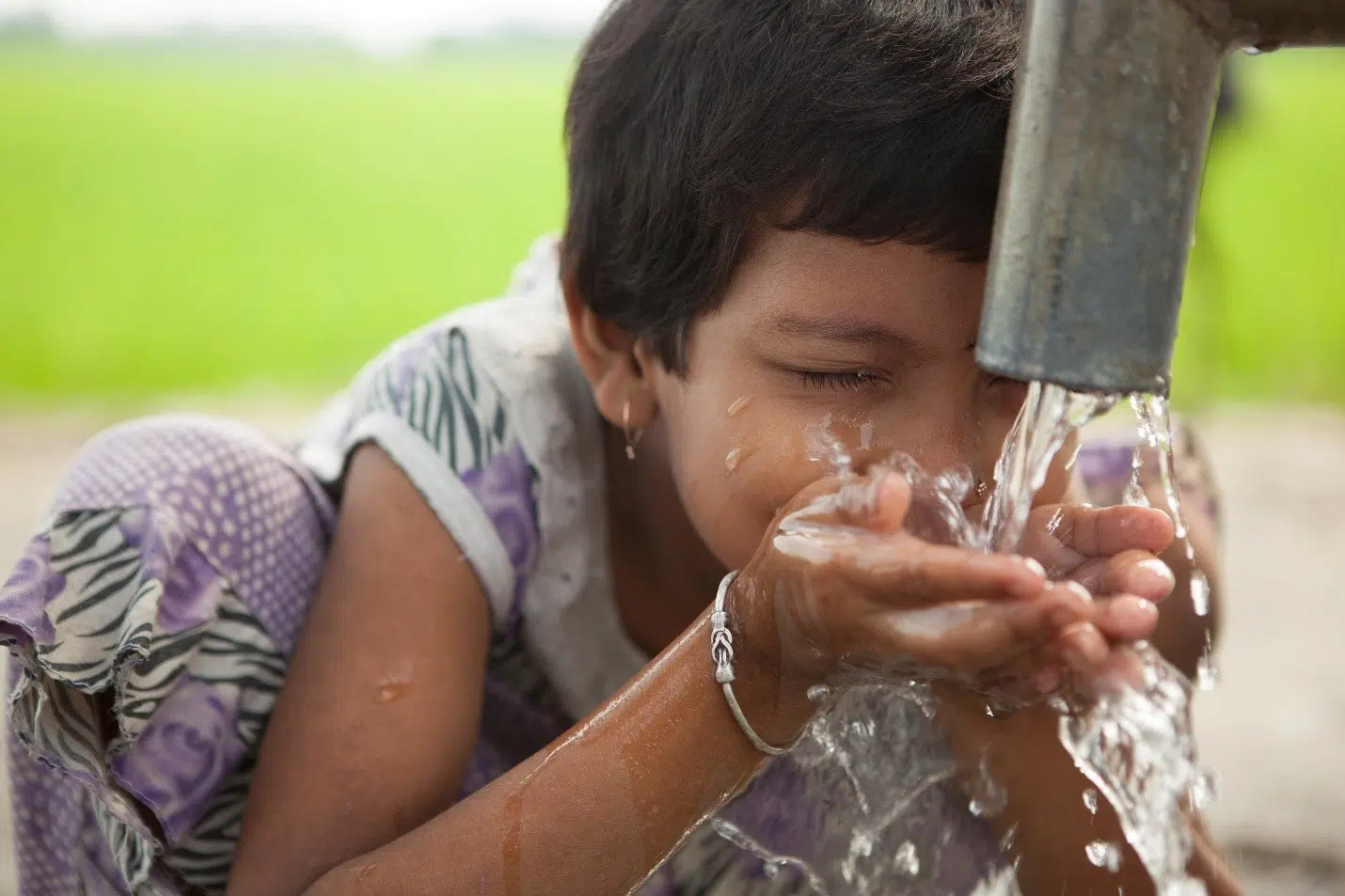 Young girl drinking from water tap