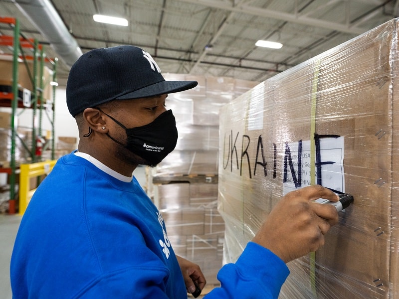 Man writing 'Ukraine' on a box in a distribution center