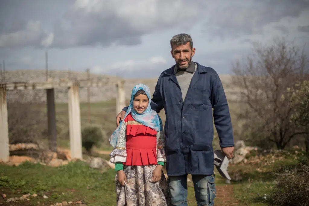 A middle eastern father posing with his daughter out in the field