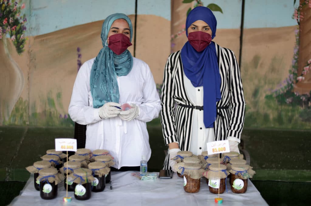 Two girls at a table selling jarred goods