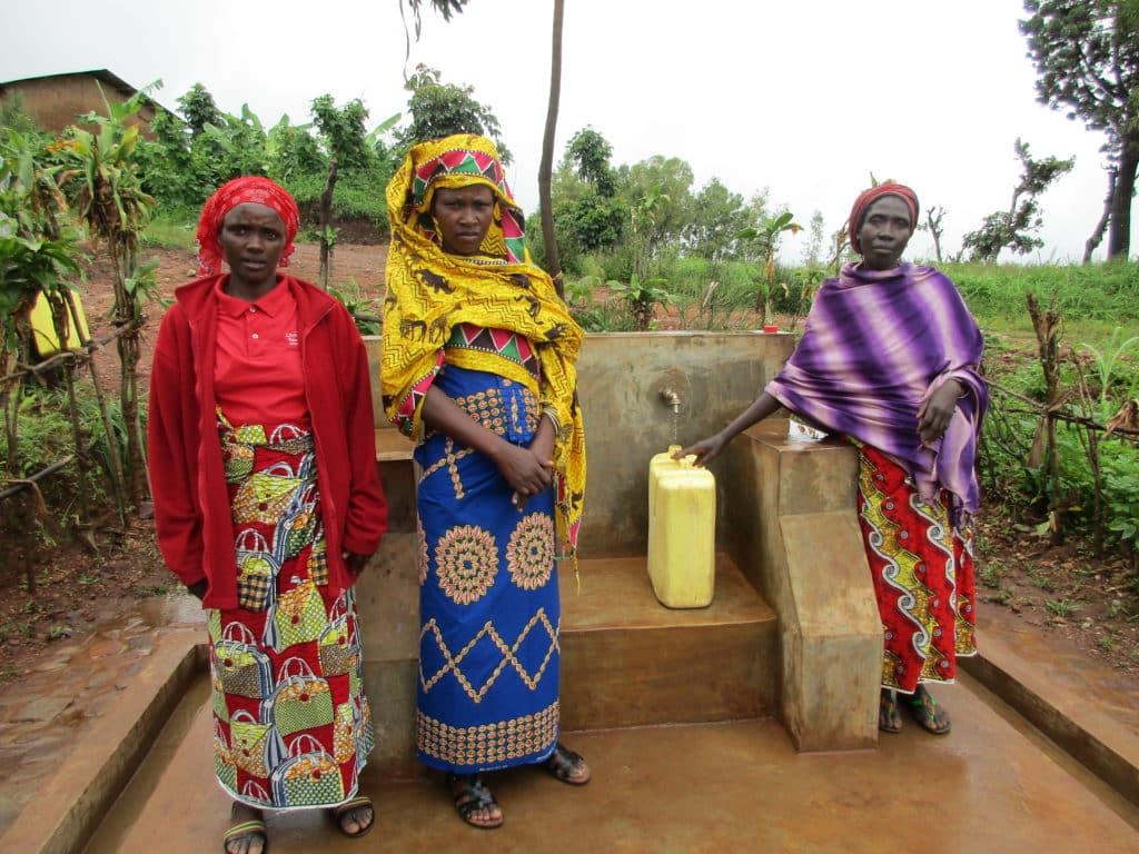 Members of the Water Committee stand next to their community tap stand.