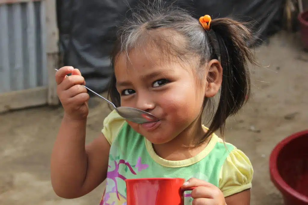 Young girl eating from a spoon at her mouth