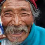 An older man smiling with a small bandage by his eye
