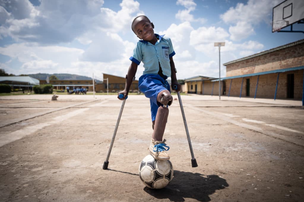 Boy on crutches has a soccer ball at his feet