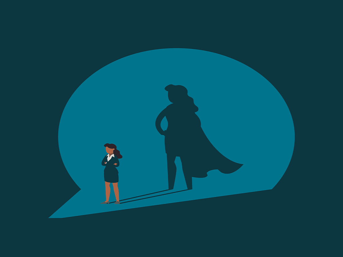 A business woman standing with a shadow of herself wearing a hero cape behind