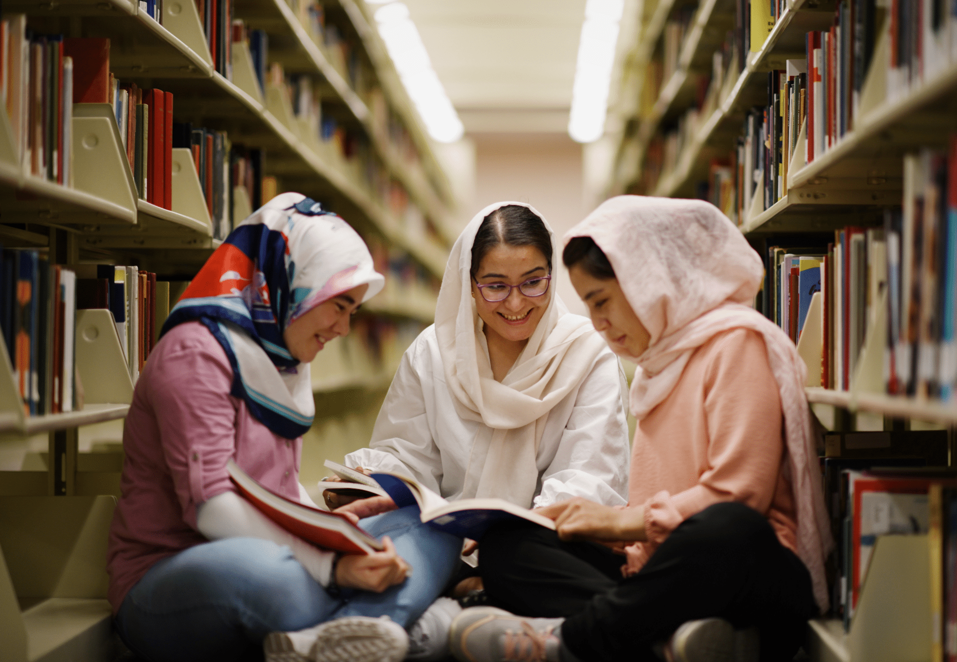 Three girls sitting together in a library.