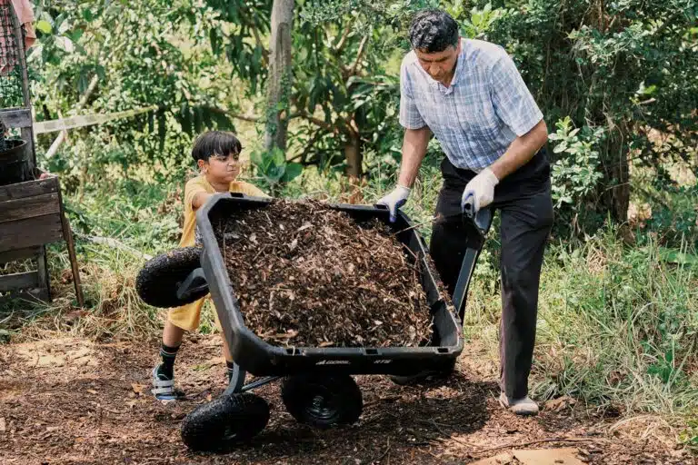 Rahmatullah Hamkar and Zekkra Sayed Jan, 10, lay down fresh soil as they work to expand the Refugee Garden in Clearwater, Florida on June 1, 2023.