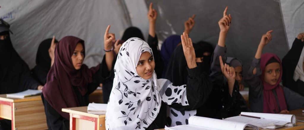 Children raise their hands at school.