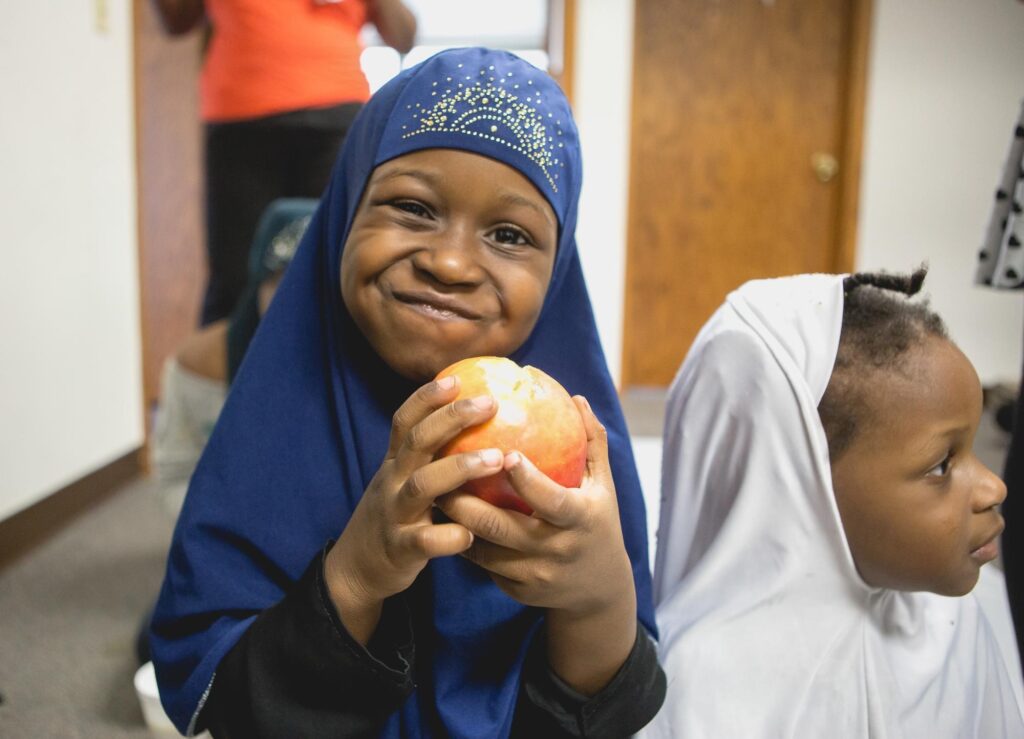 A girl holding a fruit and smiling