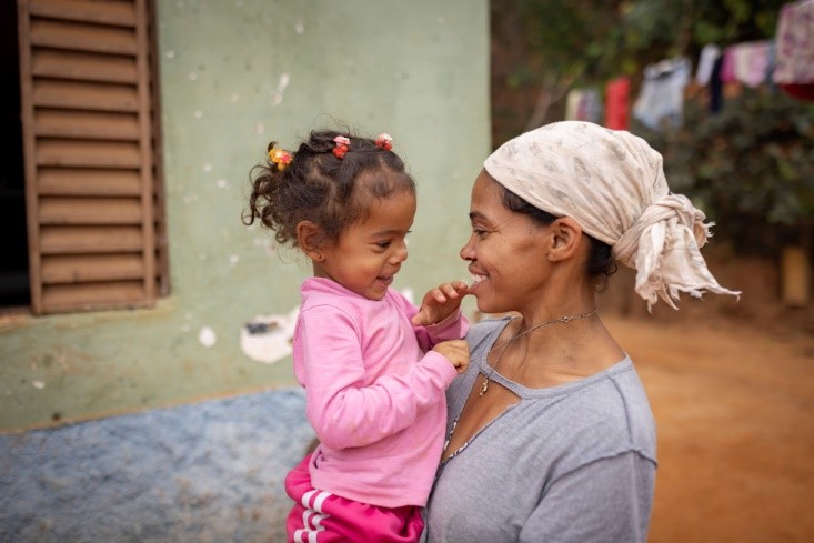 Mother in Brazil holds her daughter, smiling.
