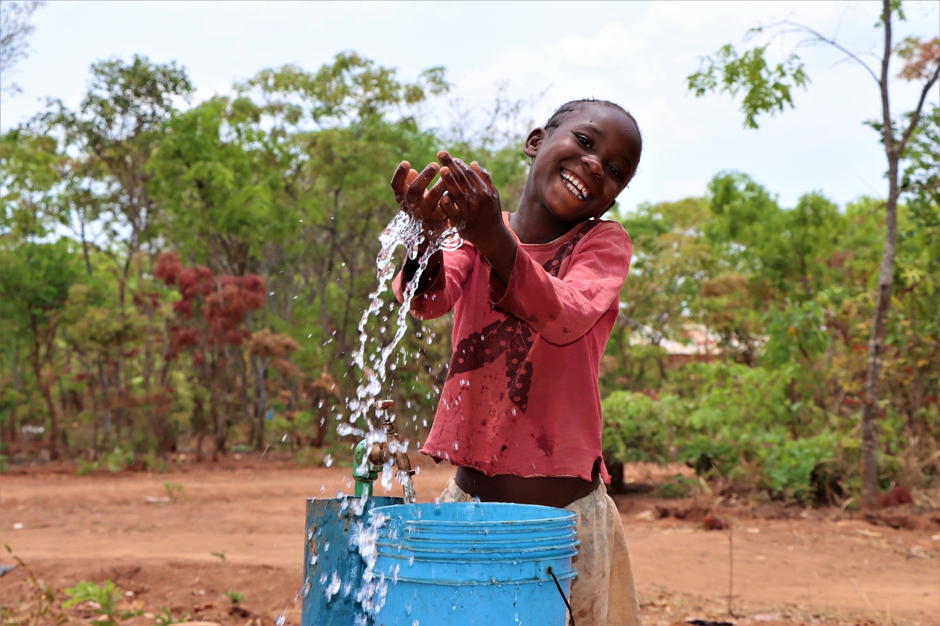 Mercy delighted to see water which is right outside her house.