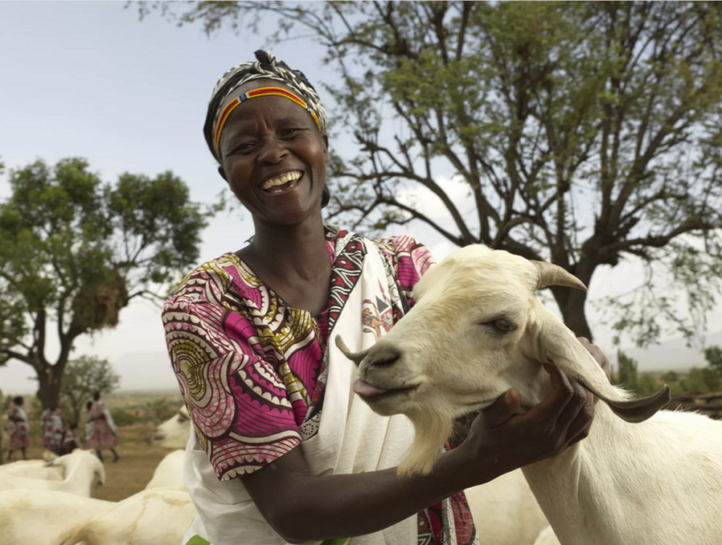 A woman smiling and posing with a goat