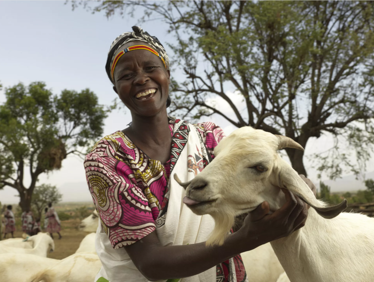 A woman smiling and posing with a goat