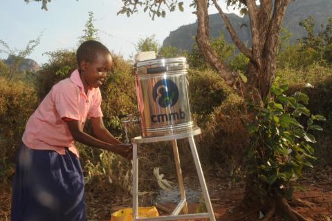 Girl washing hands with water water can