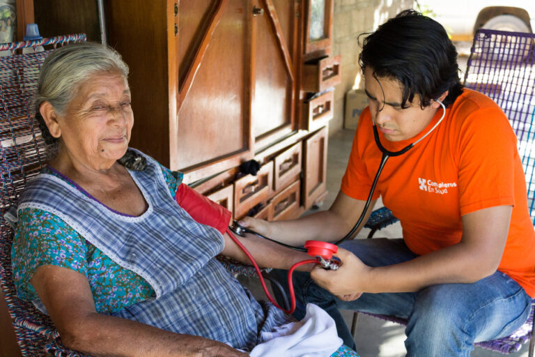Dr. Gerardo Murillo, a young Mexican doctor completing his social service year with CES, checks the blood pressure of an elderly patient, María Hernández Velásquez, during a home visit.