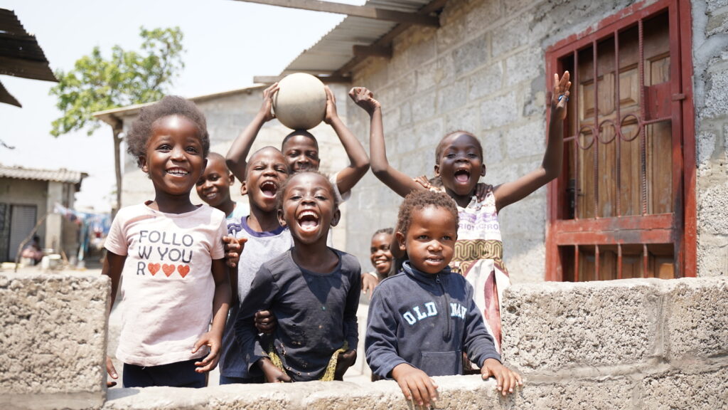 Children smiling and posing with a ball