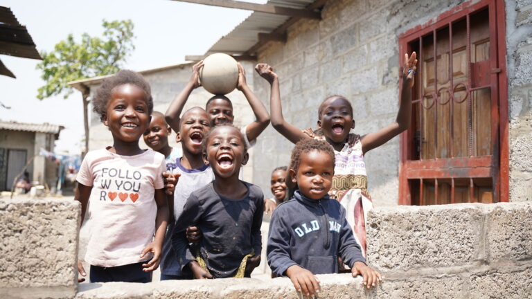 Children smiling and posing with a ball