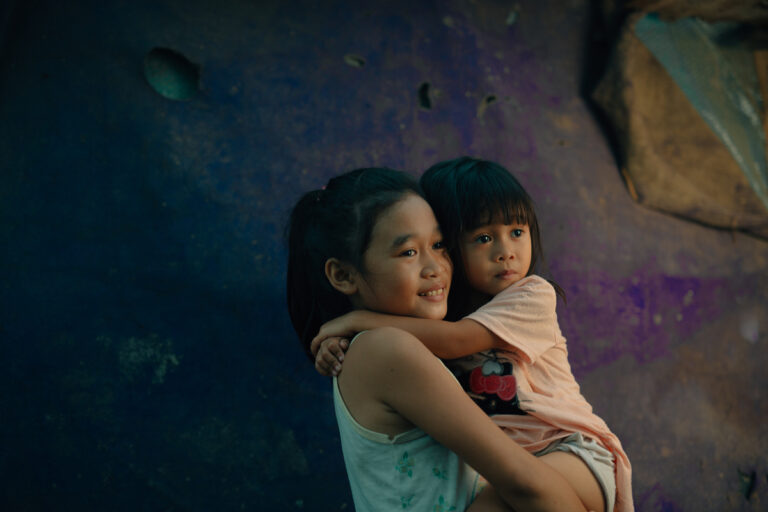 A young girl holding an even younger girl