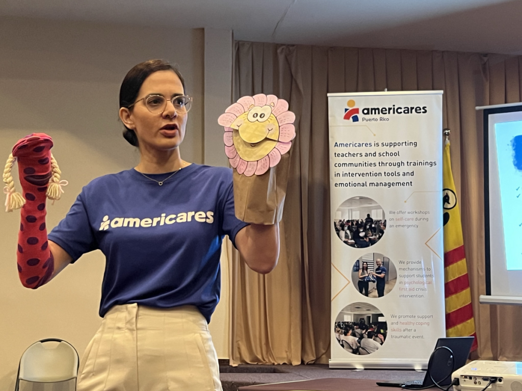 Americares member holding puppets as part of a mental health training program.