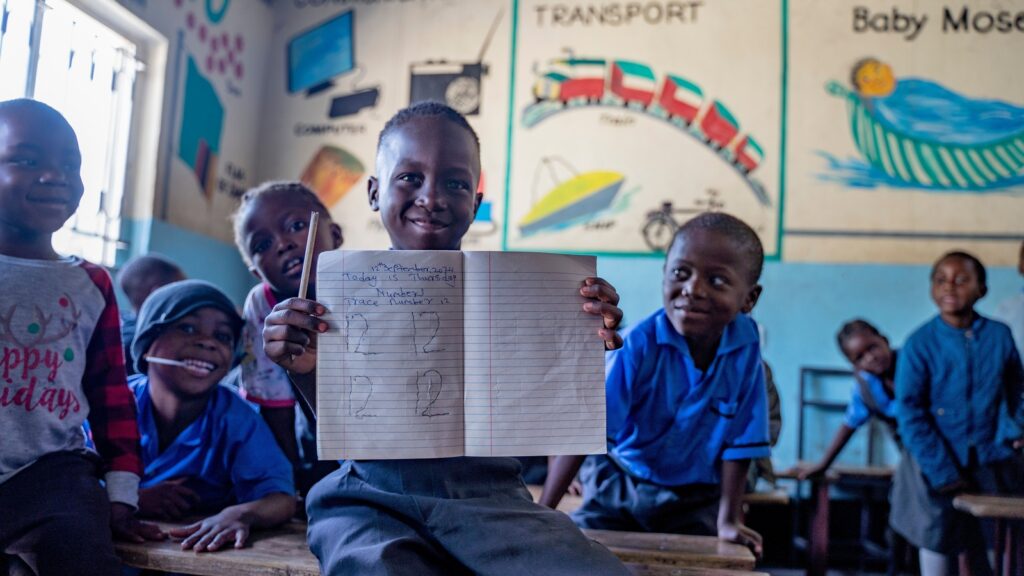 In Zambia, young learners proudly showcase their progress in a Children International early childhood program—where education begins with confidence, curiosity, and connection.
